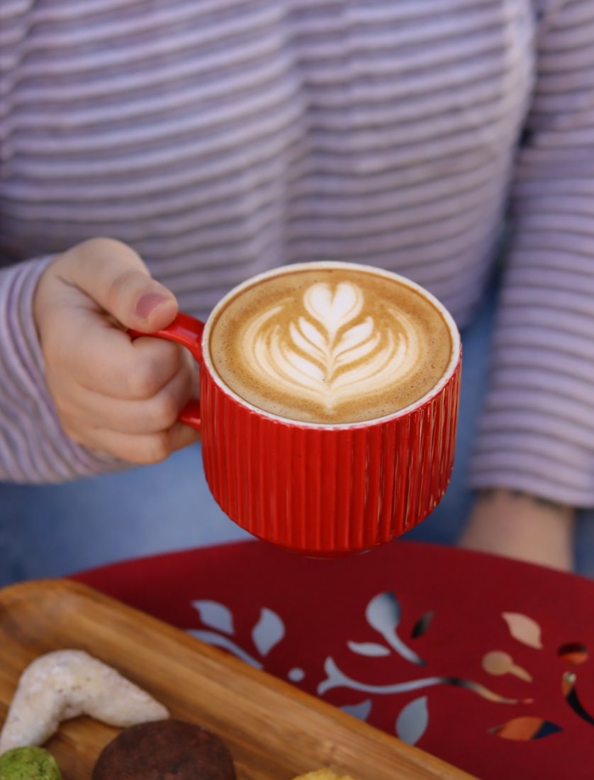 Latte art in a red ribbed cup at Le Réveil coffee shop, Upper East Side NYC