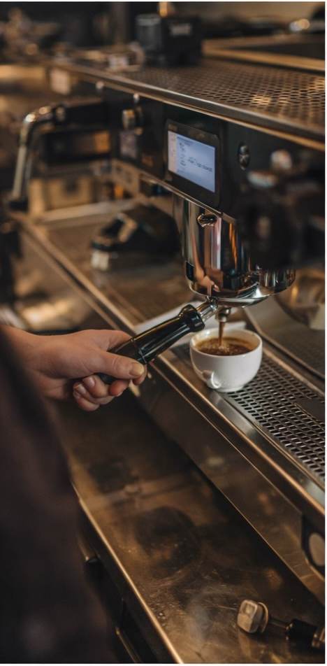 Barista pulling an espresso shot into a white cup at Le Réveil coffee shop, Upper East Side